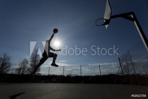 Picture of Basketball player silhouette taking off to slam dunk